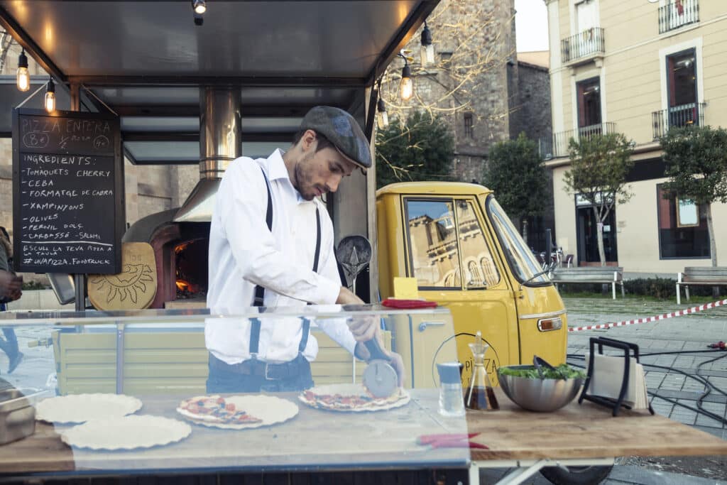 pizzaiolo préparant des pizzas artisanales devant son camion pizza food truck